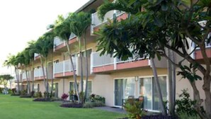 A multi-story hotel with balconies, large windows, and tropical landscaping.