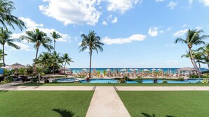 Un complexe hôtelier doté d’une piscine, de palmiers et offrant une vue sur un ciel dégagé.