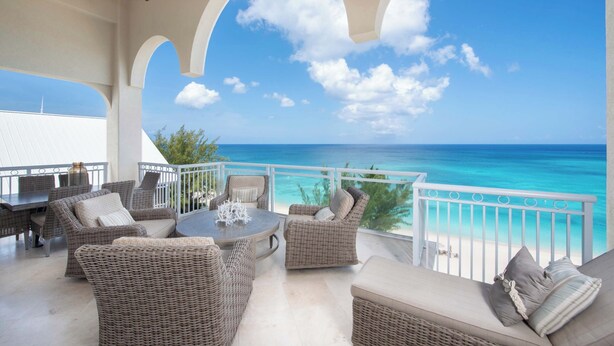 Een balkon met rieten meubilair, een plafondventilator en uitzicht op de oceaan.
