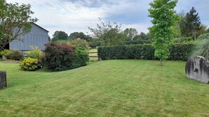 Un área verde bien cuidada, con una valla de madera, un seto y una gran estructura de piedra.