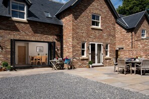 Traditional brick house with a spacious patio area, featuring a large open door and dining space.