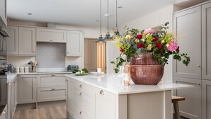 A modern kitchen with white cabinetry, a large island, and a floral centerpiece.
