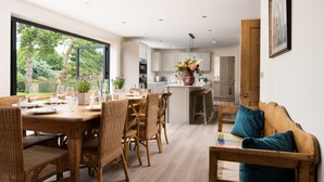 A modern kitchen with white cabinets, a central island, and a dining area with wicker furniture.