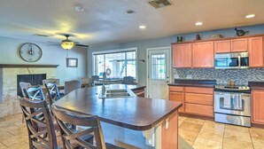 A kitchen with a central island, stainless steel appliances, and wooden cabinets.