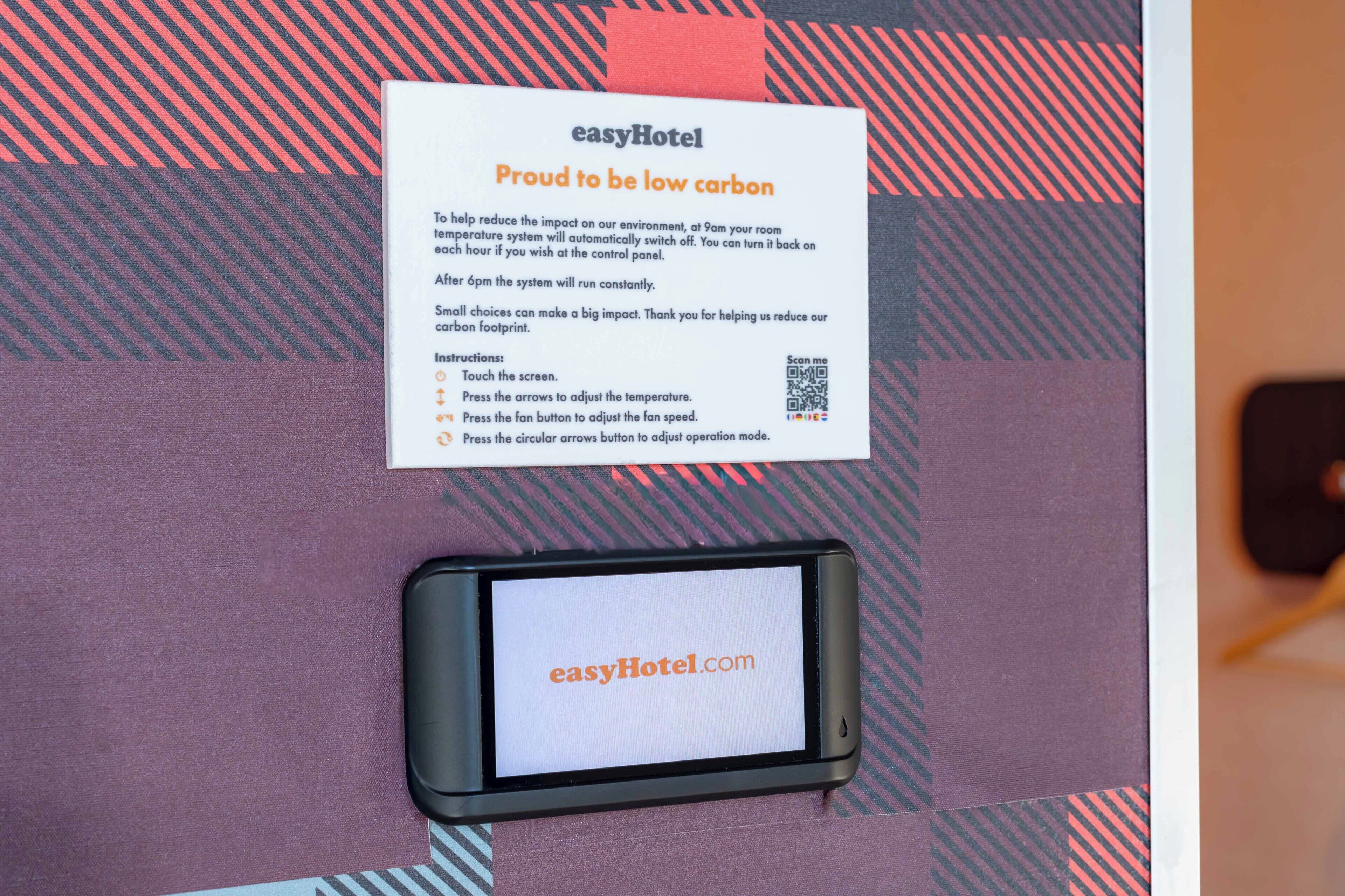 Segnaletica di un hotel con istruzioni per un sistema a temperatura a basso impatto ambientale e un codice QR.