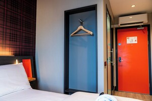 Una habitación de hotel con una cama, una puerta azul, una puerta roja y una pared con diseño escocés.