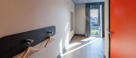 A hallway with a wooden coat rack, a door, and a view through a window.