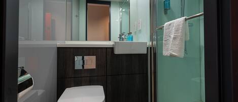 A modern bathroom with a toilet, a sink, and a glass-enclosed shower.