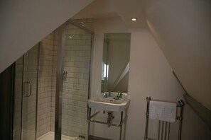 A bathroom with a glass shower enclosure, a white sink with a mirror above it, and a towel rack. - Thornton Manor Estates (Wirral)