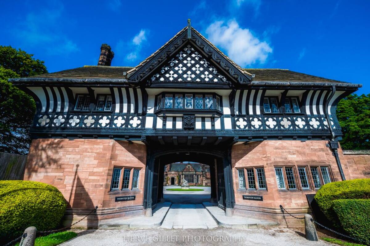 A Tudor-style building with a symmetrical facade, a central entrance, and a well-maintained lawn.