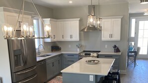 A modern kitchen with white cabinets, stainless steel appliances, and a central island. - 2026-27 October to May deep discount special pricing! Please contact for rates! (Port Sranley)