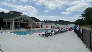 A pool area with lounge chairs, a covered seating area, and a building with large windows. - 2026-27 October to May deep discount special pricing! Please contact for rates! (Port Sranley)