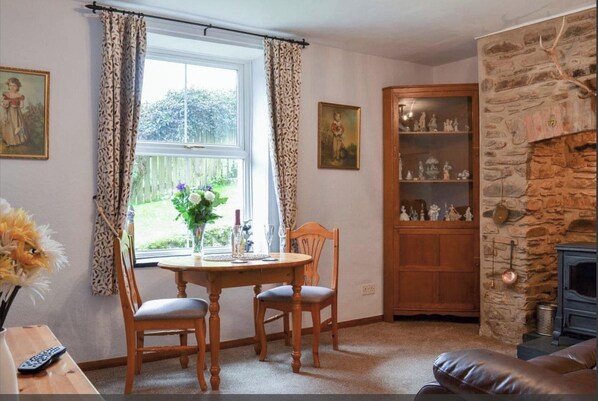 A cozy room with a stone fireplace, a wooden cabinet with figurines, and a dining area with a table and chairs.