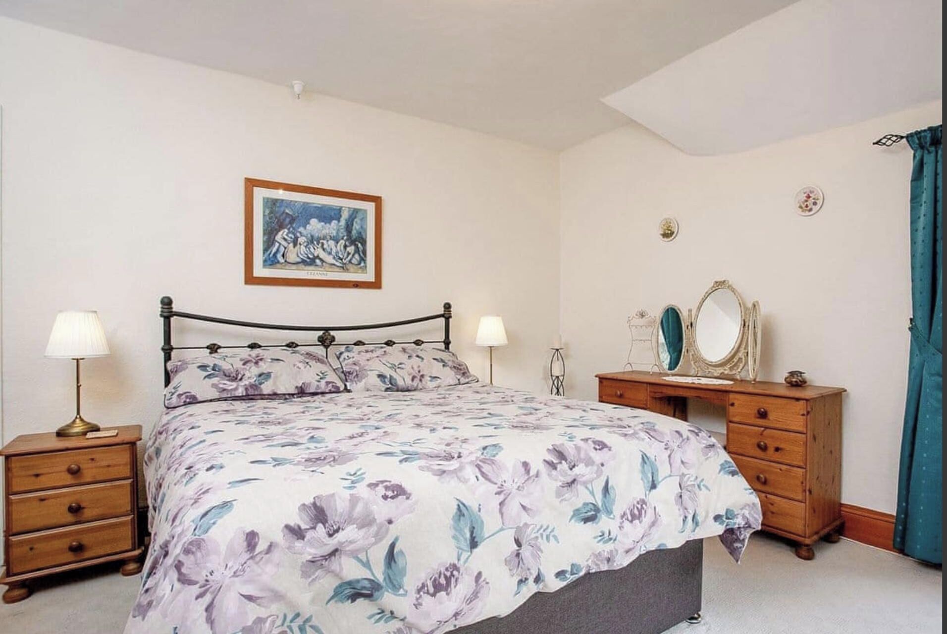 A bedroom with a bed, two bedside tables, a dresser, a mirror, and a framed picture on the wall.