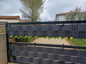 A black metal gate with yellow flowers in front.
