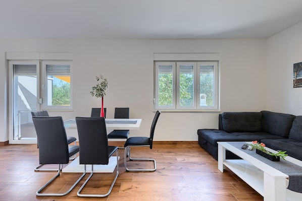 Un salon moderne avec un coin repas, un plancher en bois et de grandes fenêtres.