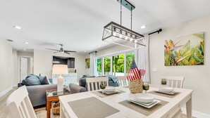 A modern dining area with a white table set for four, featuring a centerpiece with an American flag and wine glasses. - Updated Home with Outdoor Dining and heated Pool! 2 Minutes to Beach! - Native S (Holmes Beach)