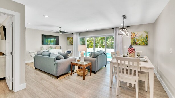 A spacious living area with a pool, two sofas, a dining table, and a ceiling fan. - Updated Home with Outdoor Dining and heated Pool! 2 Minutes to Beach! - Native S (Holmes Beach)