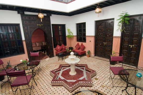 A courtyard with a fountain, seating area, and traditional doors. - Unforgettable stay in Marrakech (Marrakesh)