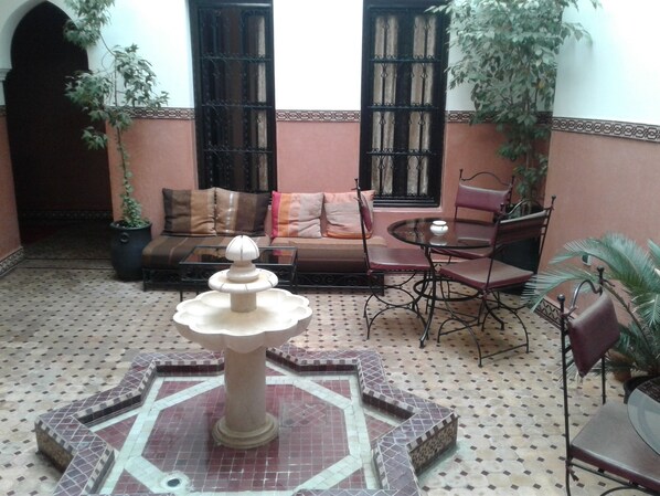 A courtyard with a fountain, seating area, and potted plants. - An Unforgettable Stay in Marrakesh (Marrakesh)
