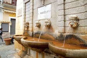 Un muro in pietra con diverse bocchette d'acqua e una targa con l'iscrizione 'A. MDCCLXVI'.