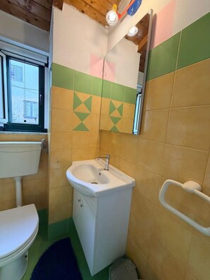 Un bagno con il water, un lavandino e una finestra.