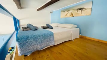 Una stanza con un letto, una parete blu e un pavimento in legno.