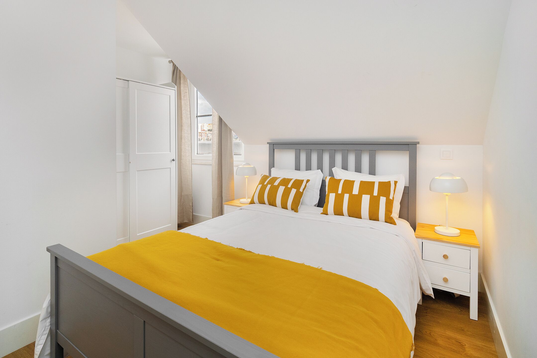Un dormitorio ordenado con cama, mesitas de noche y ventana.