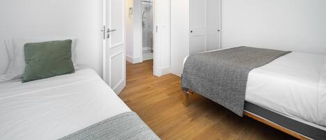 A bedroom with two beds, a walk-in closet, and a shower area.