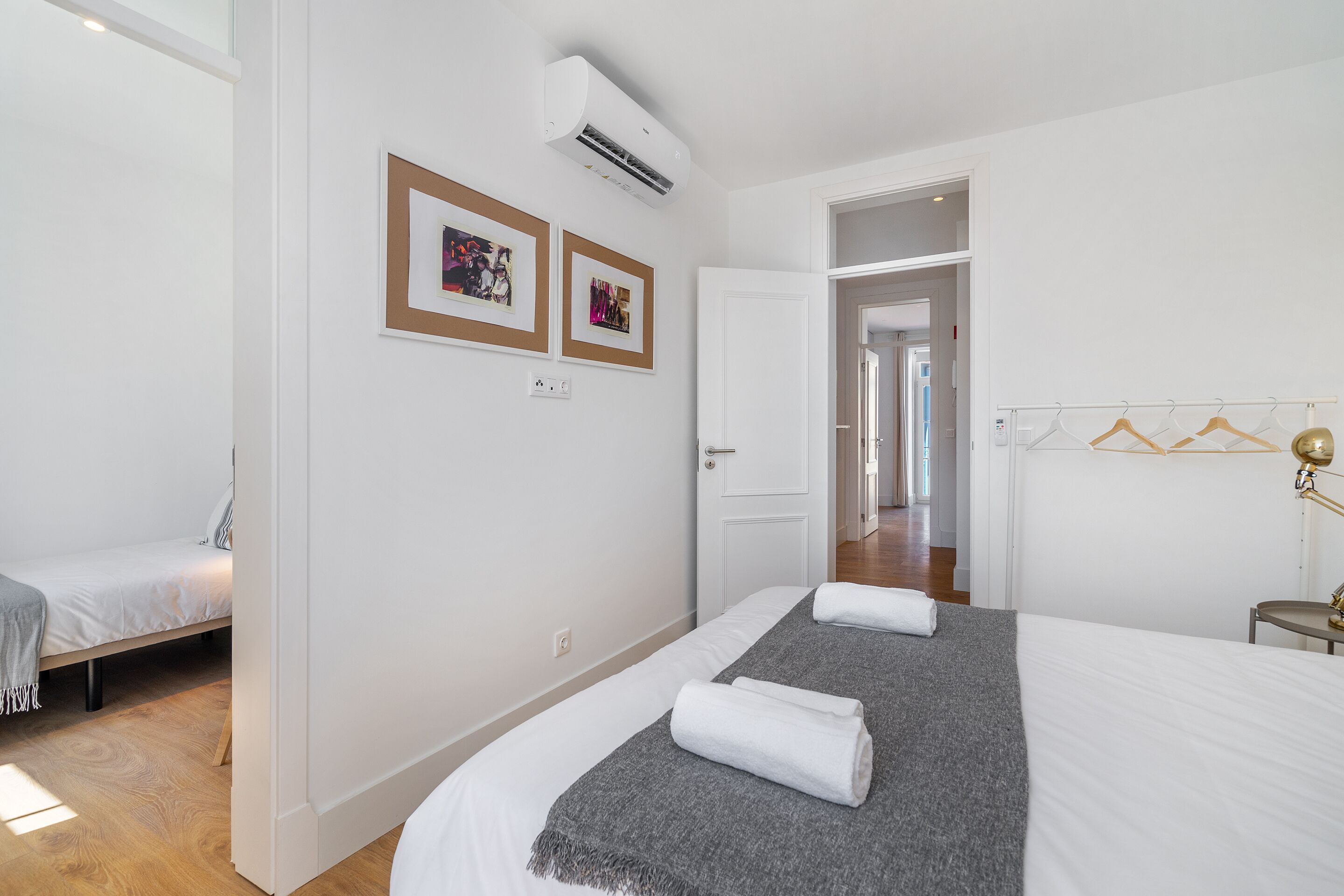 A hotel room with a large bed, a smaller bed, a wardrobe, and a door leading to another room.