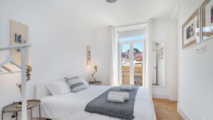 A bedroom with a bed, bedside tables, a lamp, and a view through an open door.