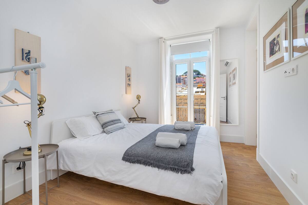 A bedroom with a bed, bedside tables, a lamp, and a view through an open door.