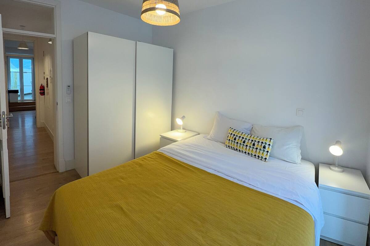 A bedroom with a bed, bedside tables, a wardrobe, and a hanging light fixture.