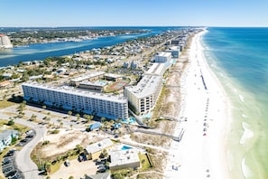An aerial view of a coastal hotel with multiple buildings, a beach, and a marina.