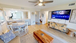 Uma sala de estar moderna com televisão, móveis de madeira e ventilador de teto.