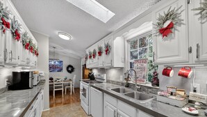A kitchen with white cabinets, a marble countertop, and Christmas decorations. - Twin Ponds Retreat-Pond/Hot Tub/Fire Pit/Game Room/Pet Friendly by RedAwning (Whittier)