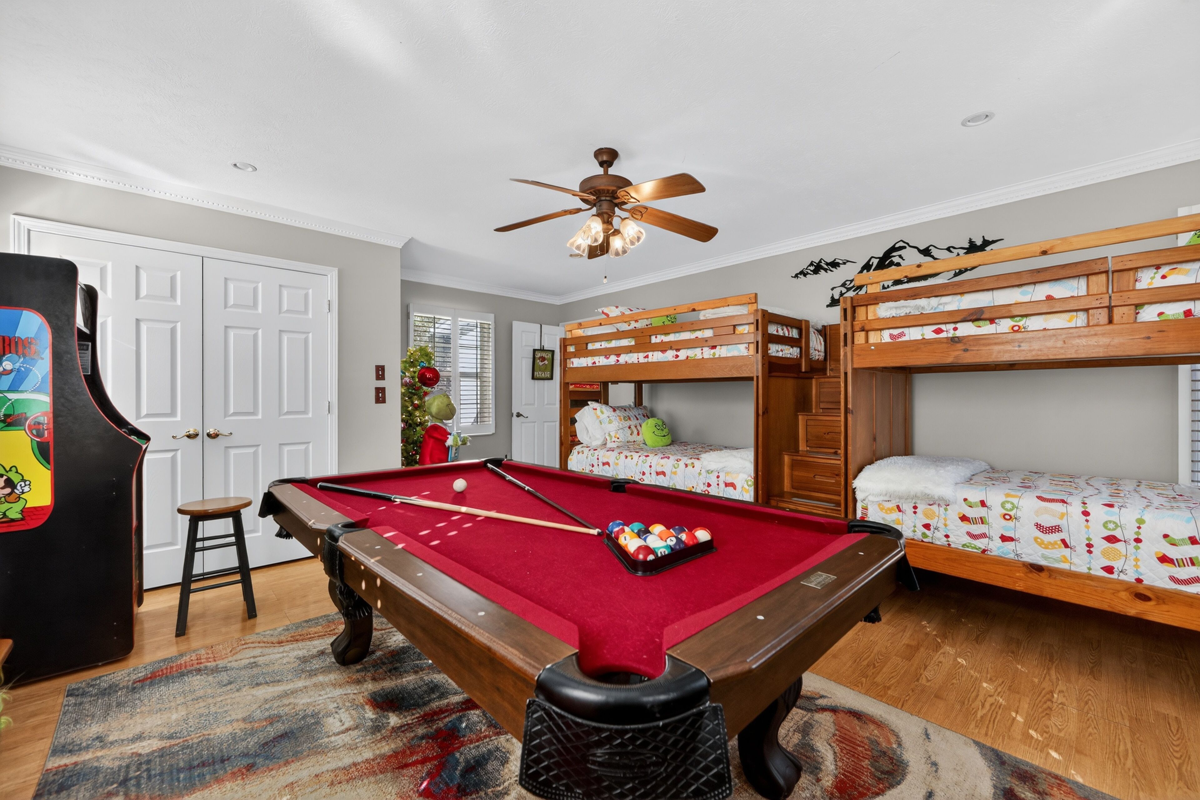 A room with a pool table, bunk beds, a ceiling fan, and a door.