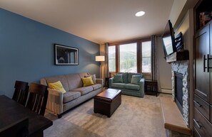 A living room with two sofas, a coffee table, a TV, and a fireplace. - Mountain View Ski-In Ski-Out Condo - Zephyr Mountain Lodge Premium-Rated 2516 (Winter Park)