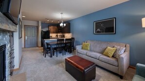A living room with a sofa, a coffee table, and a fireplace. There is a dining area with a table and chairs. - Mountain View Ski-In Ski-Out Condo - Zephyr Mountain Lodge Premium-Rated 2516 (Winter Park)