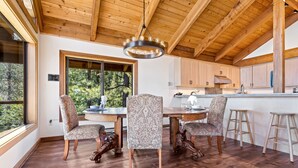 A wooden ceiling, a dining table with chairs, and a kitchen area with cabinets and stools. - AMAZING VIEWS- MODERN HOME- SH #14 by Bear Valley Vacation Rentals (Arnold)