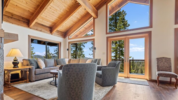 A spacious living room with a high ceiling, large windows, and a cozy seating area. - AMAZING VIEWS- MODERN HOME- SH #14 by Bear Valley Vacation Rentals (Arnold)