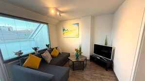 Een moderne woonkamer met een bank, een salontafel en een flatscreen televisie.