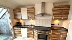Een moderne keuken met houten kastjes, een roestvrijstalen afzuigkap, een inbouwoven en een zwart aanrecht.