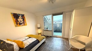 Een slaapkamer met een bed, een stoel, een schilderij, een lamp en uitzicht door een schuifdeur.