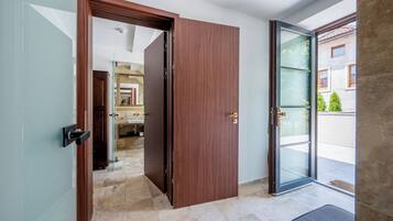 Ein modernes Interieur mit einer Holztür, die ins Bad führt, und einer Glastür zu einem Außenbereich.