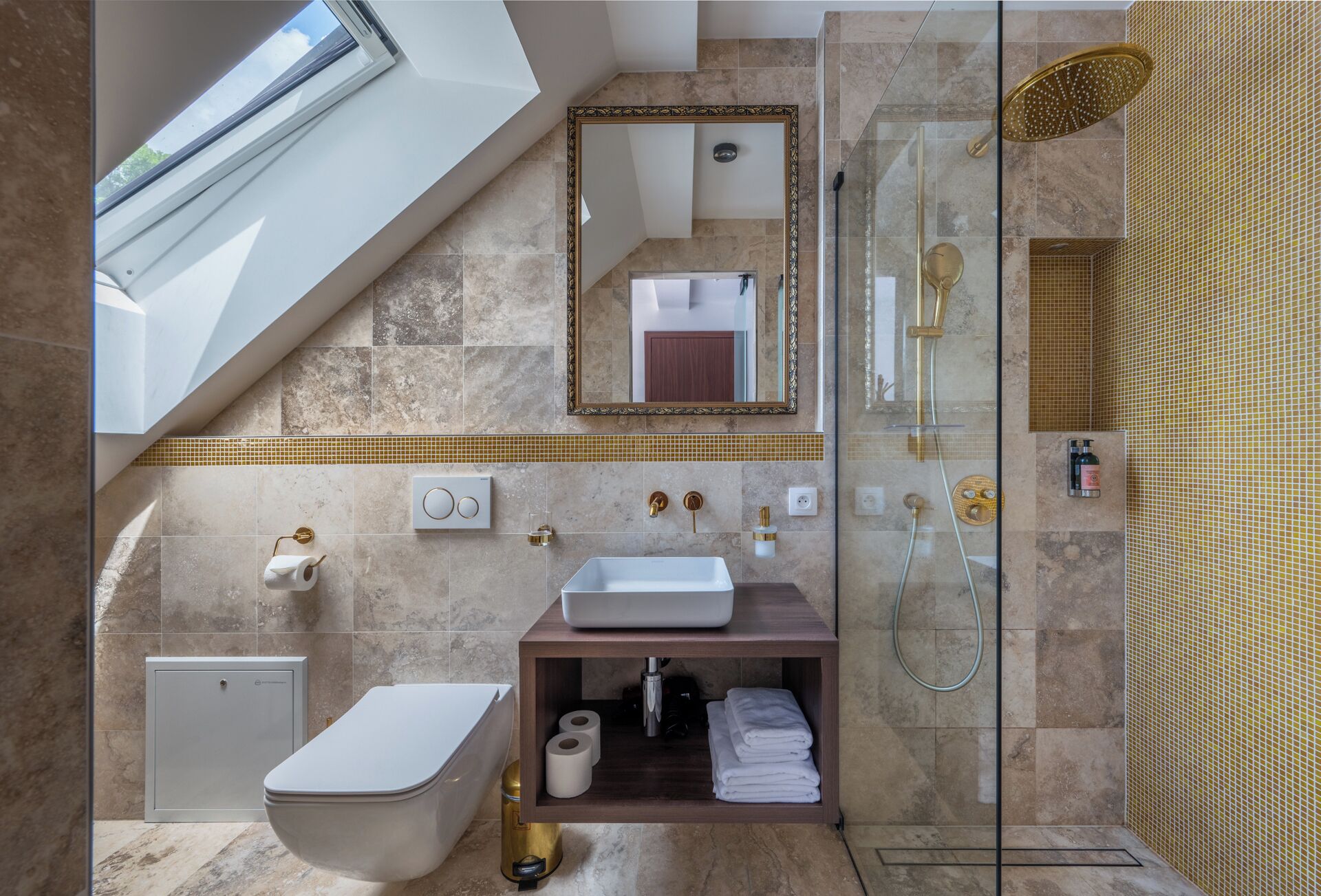 A modern bathroom with a skylight, a glass-enclosed shower, a vanity with a sink, and a toilet.