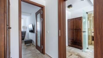 A hallway with wooden doors, a grey sofa, and a television.