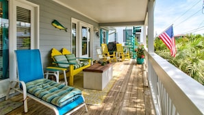 Une véranda avec un plancher en bois, une chaise bleue, une chaise jaune, une petite table et un drapeau américain.