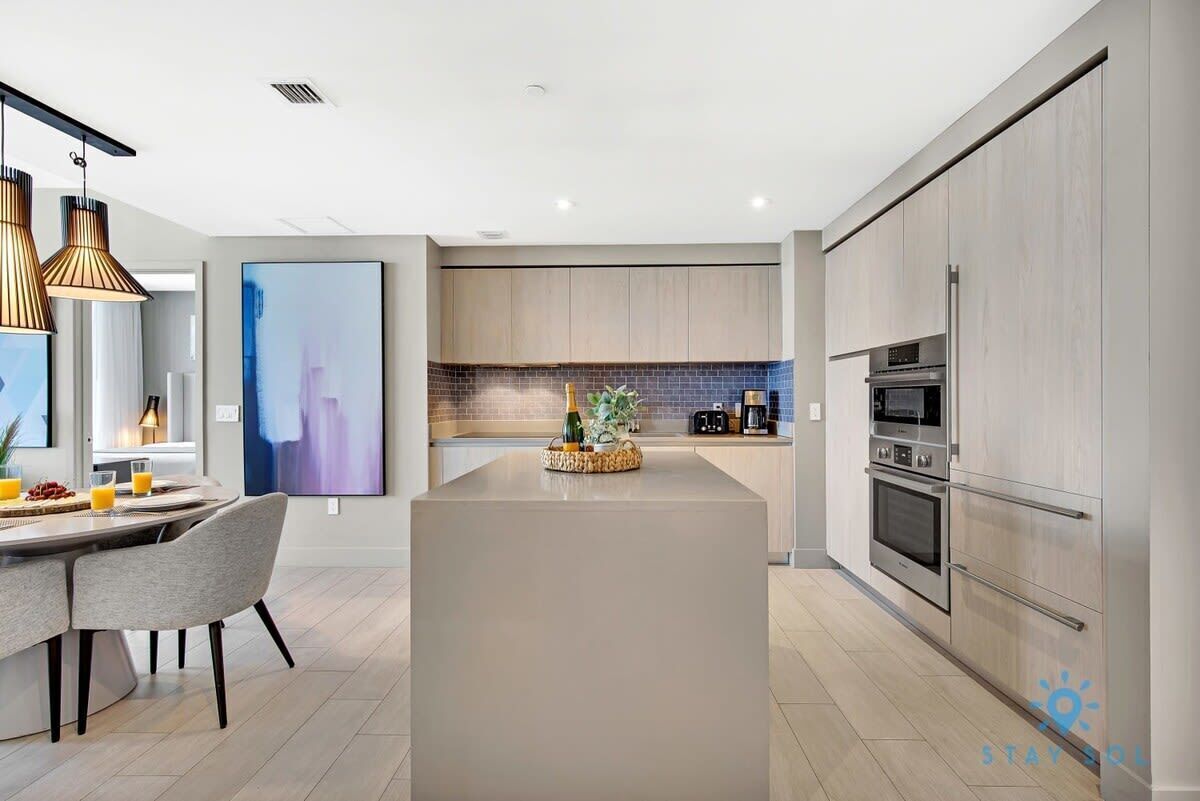 A modern kitchen with a central island, built-in appliances, and pendant lighting.