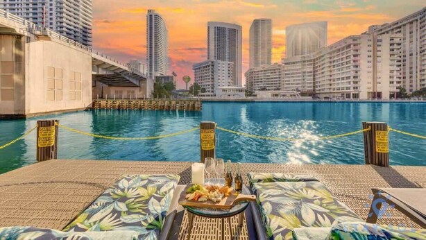 Une vue sur la piscine, avec des chaises longues, une table à manger dressée et, en arrière-plan, le panorama de la ville.